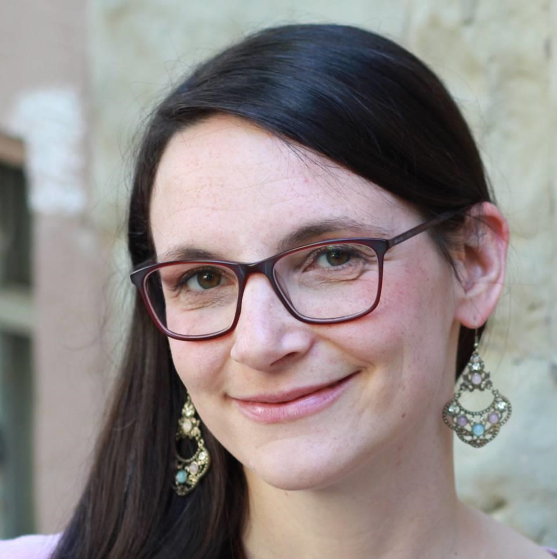 Portraitbild einer Frau mit langen dunklen Haaren und großen Ohrringen