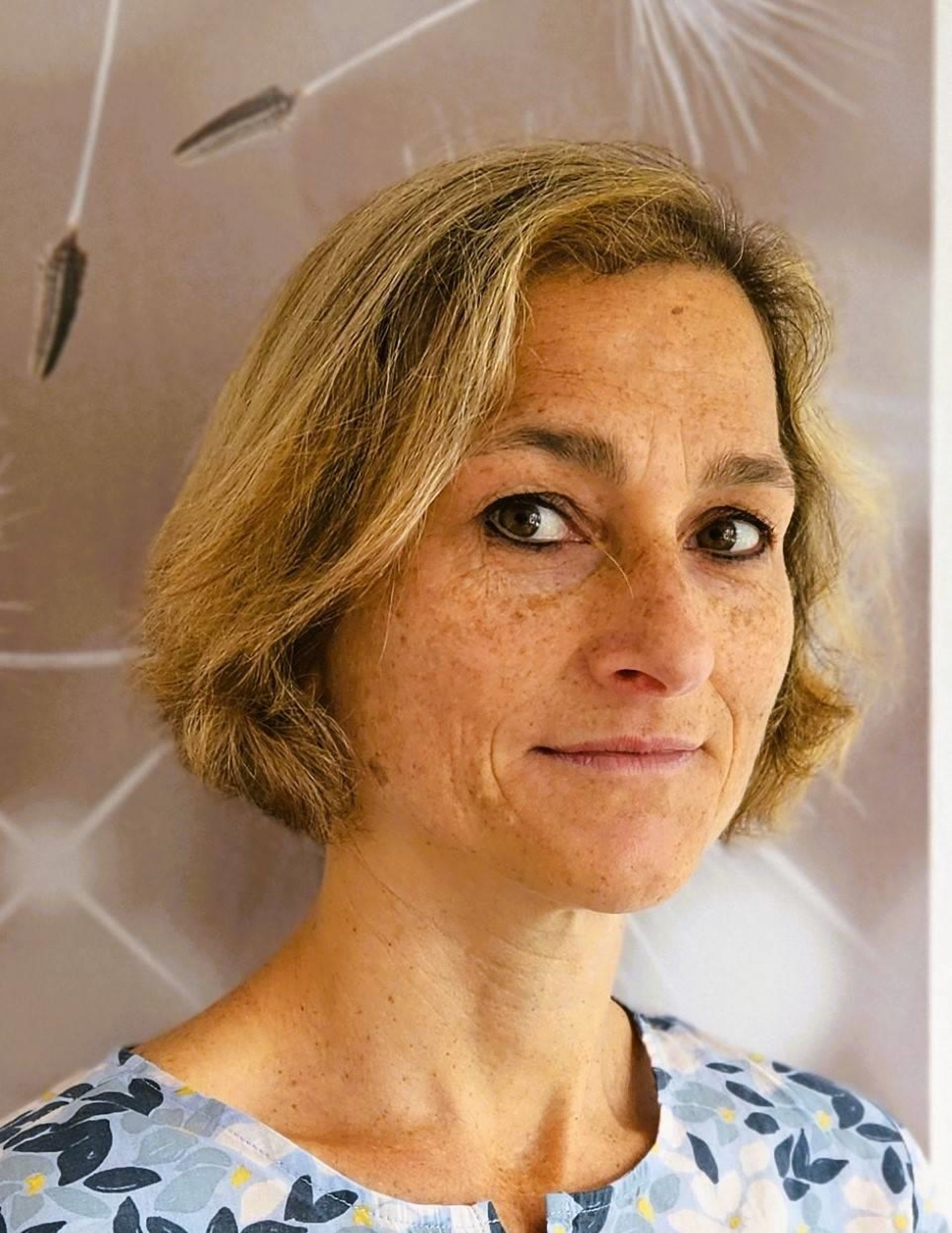 Portraitbild einer Frau mit kinnlangen blonden Haaren und Sommersprossen.