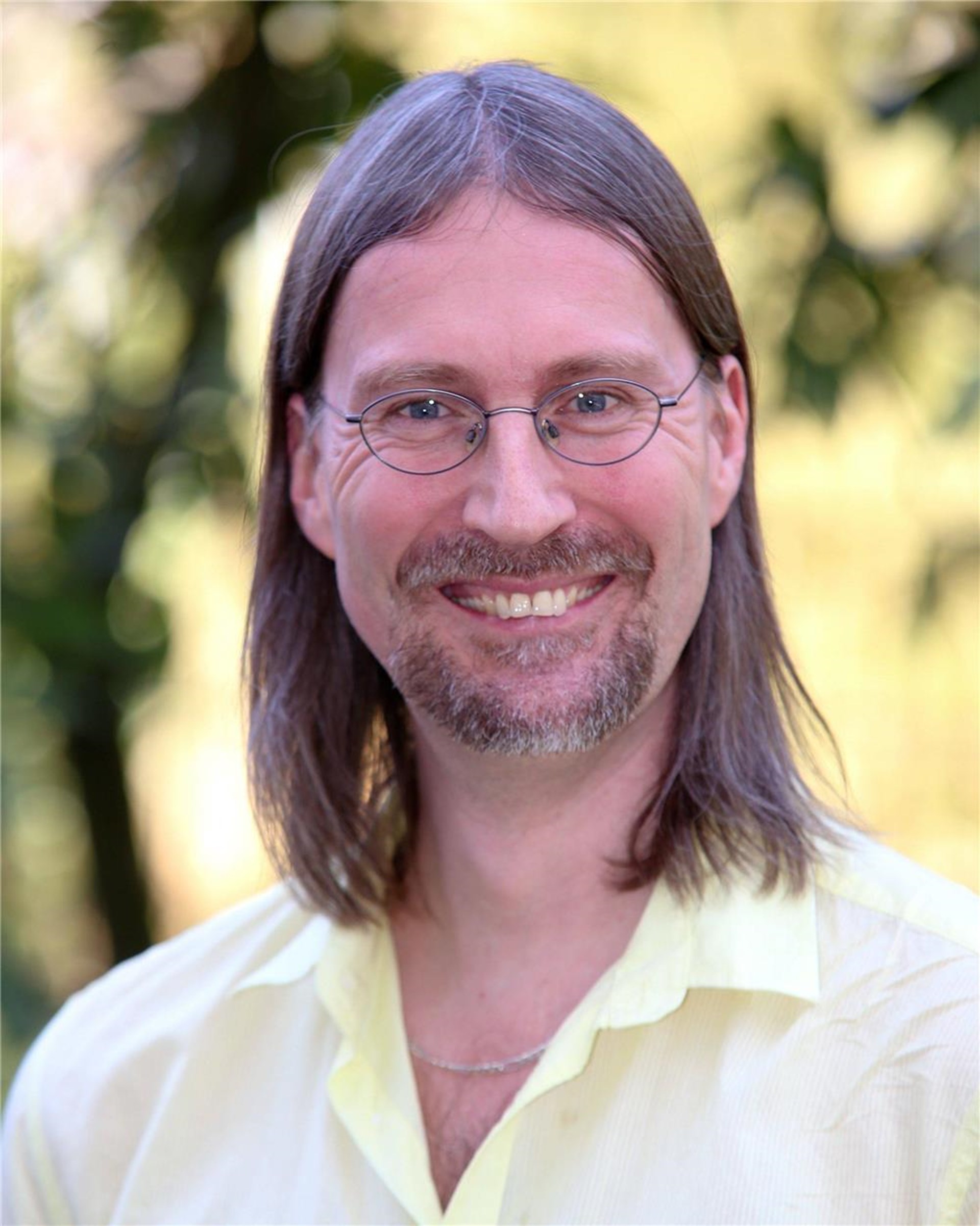 Mann mit schulterlangem braunem Haar und Brille