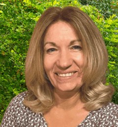 Portraitbild einer Frau mit schulterlangen Haaren und braun-weiß gemustertem Top.