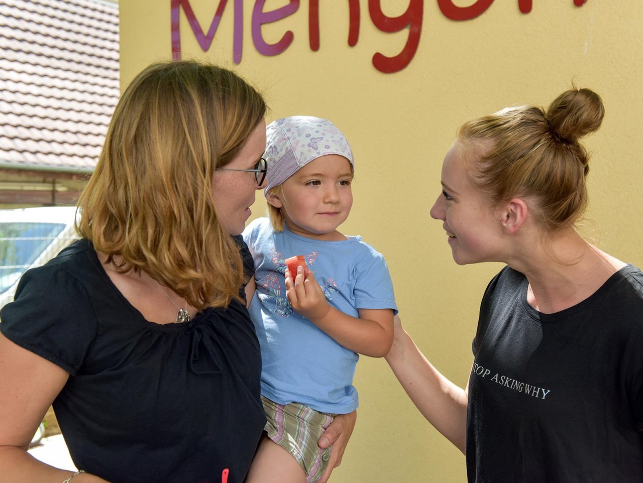 Kind mit Erzieherin und Mutter vor Kindergarten